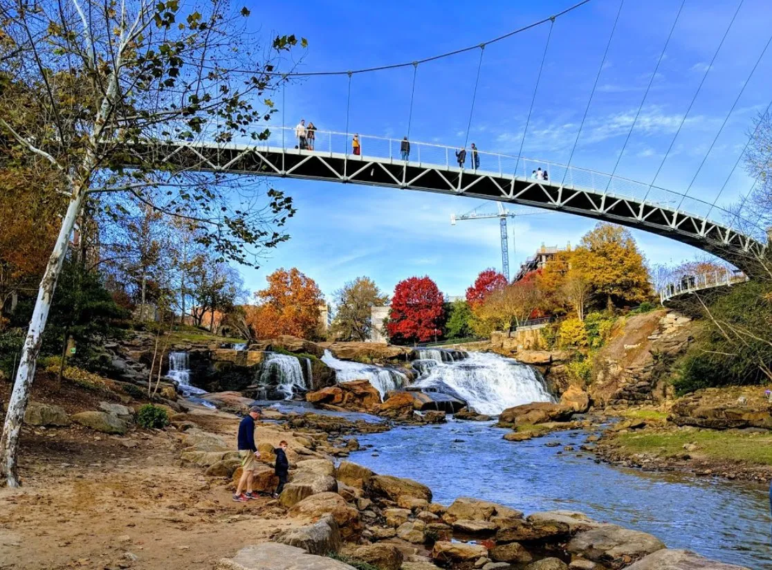 Scenic view of a suspension bridge over a waterfall in a park during autumn