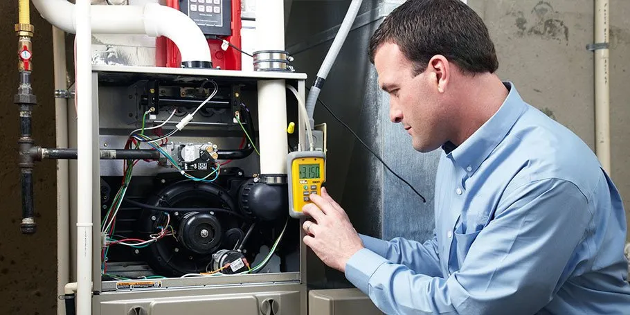 Technician inspecting and testing a furnace system with a digital meter