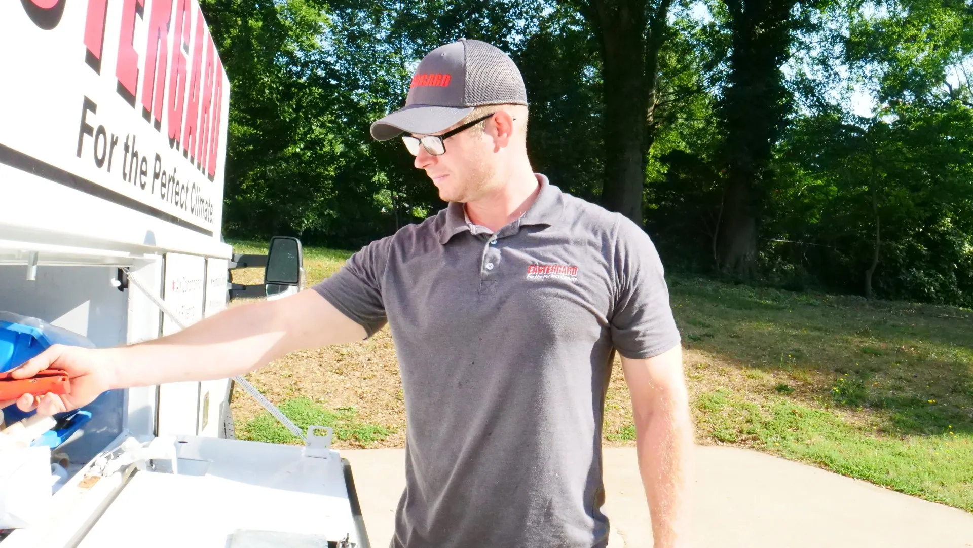 HVAC technician in an Eastergard uniform retrieving tools from a service truck
