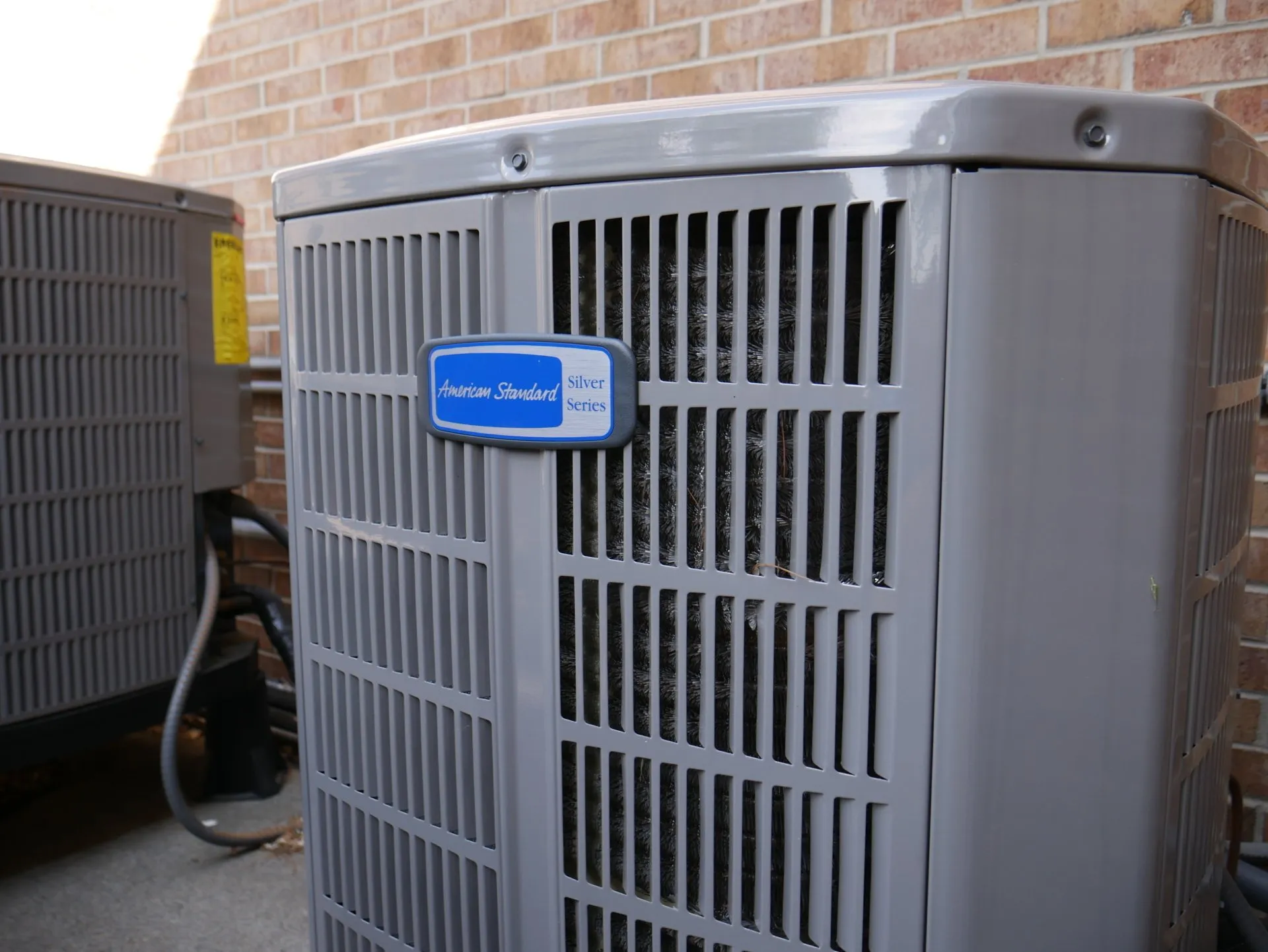American Standard Silver Series outdoor HVAC unit installed against a brick wall