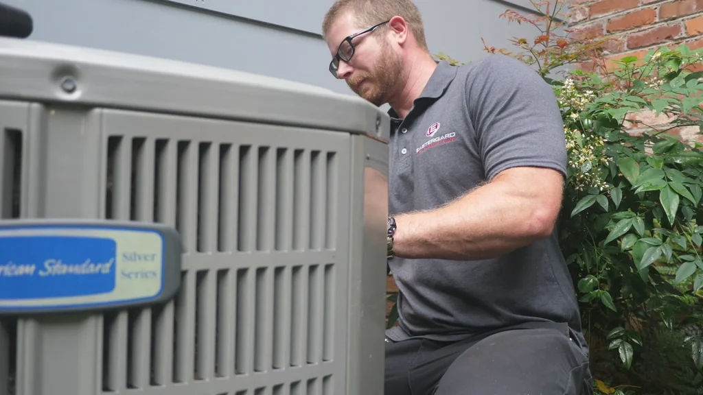 HVAC technician servicing an American Standard Silver Series outdoor unit - AC blowing warm air
