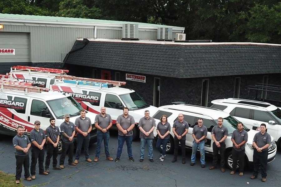 Eastergard HVAC team posing in front of company vans and office building