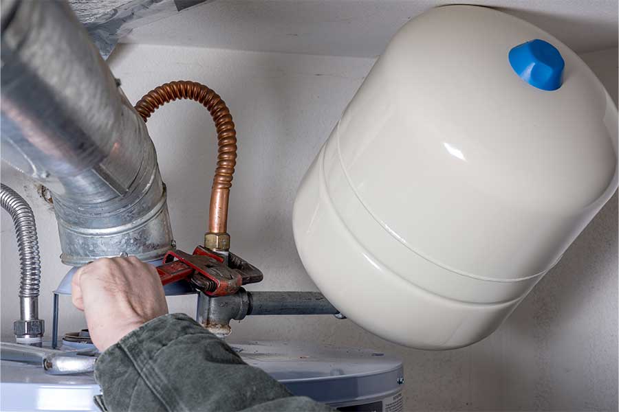 Technician installing an expansion tank on a water heater