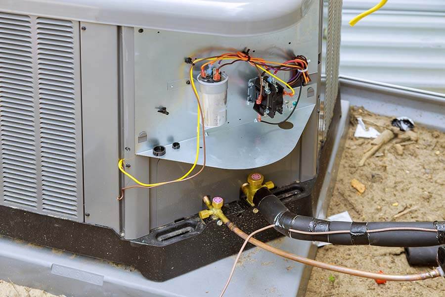 Open outdoor air conditioner showing electrical components and refrigerant lines during routine ac maintenance service