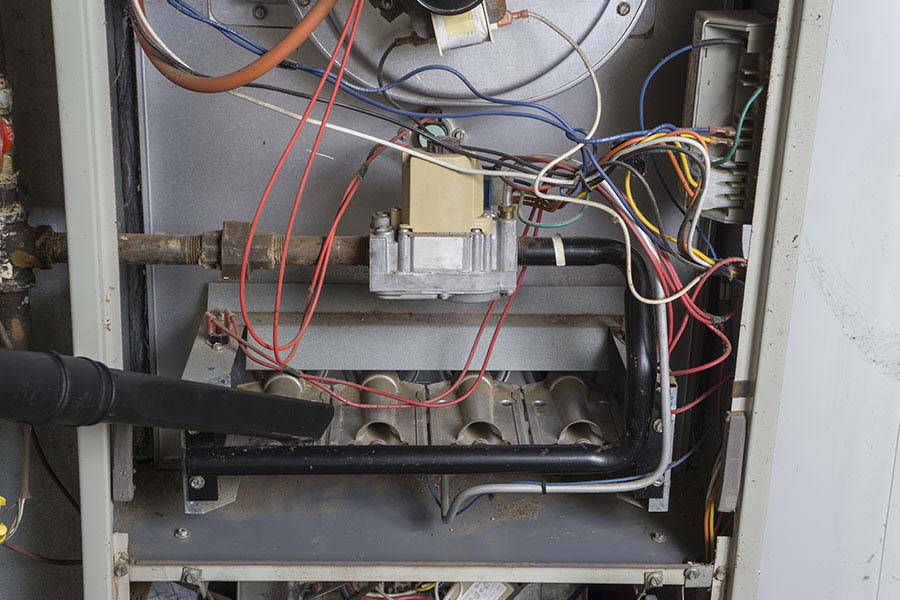 Open furnace cabinet showing internal components, wiring, gas valve, and burners during furnace repair service