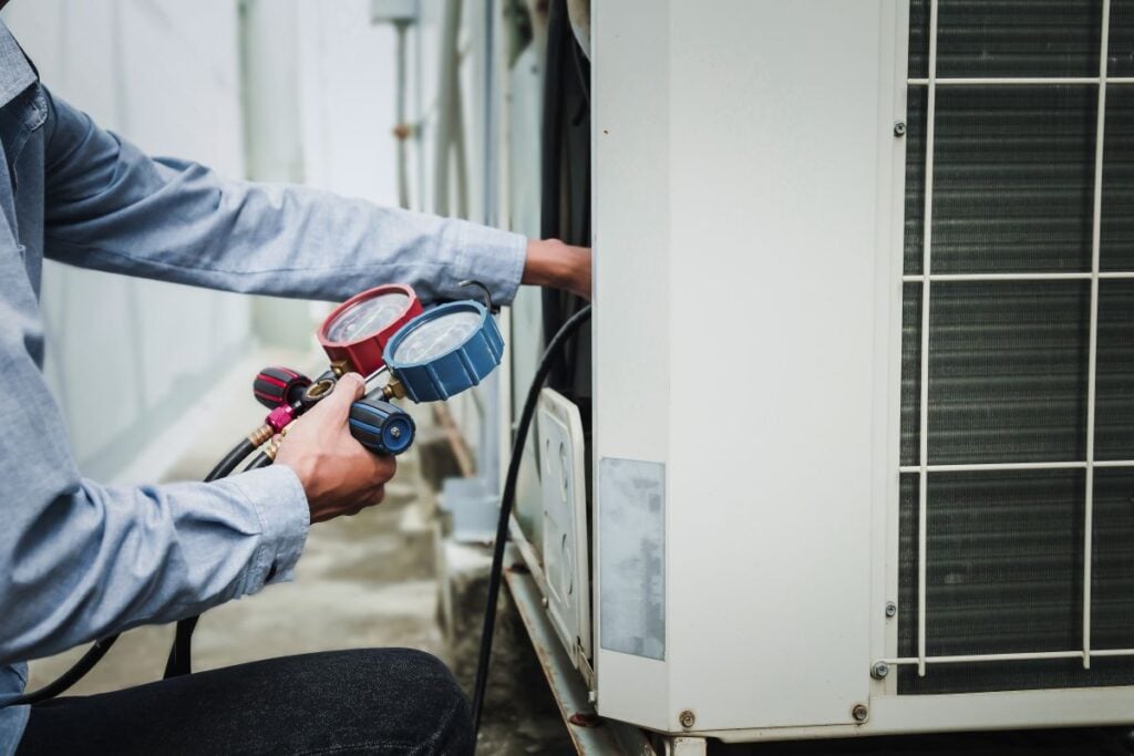 Mechanic air conditioner technician is using a manifold gauge to check the refrigerant in the system