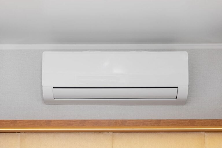 Ductless White Air Conditioner Mini Split Unit Mounted at Wall in Room