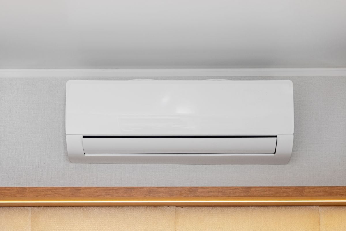 Ductless White Air Conditioner Mini Split Unit Mounted at Wall in Room