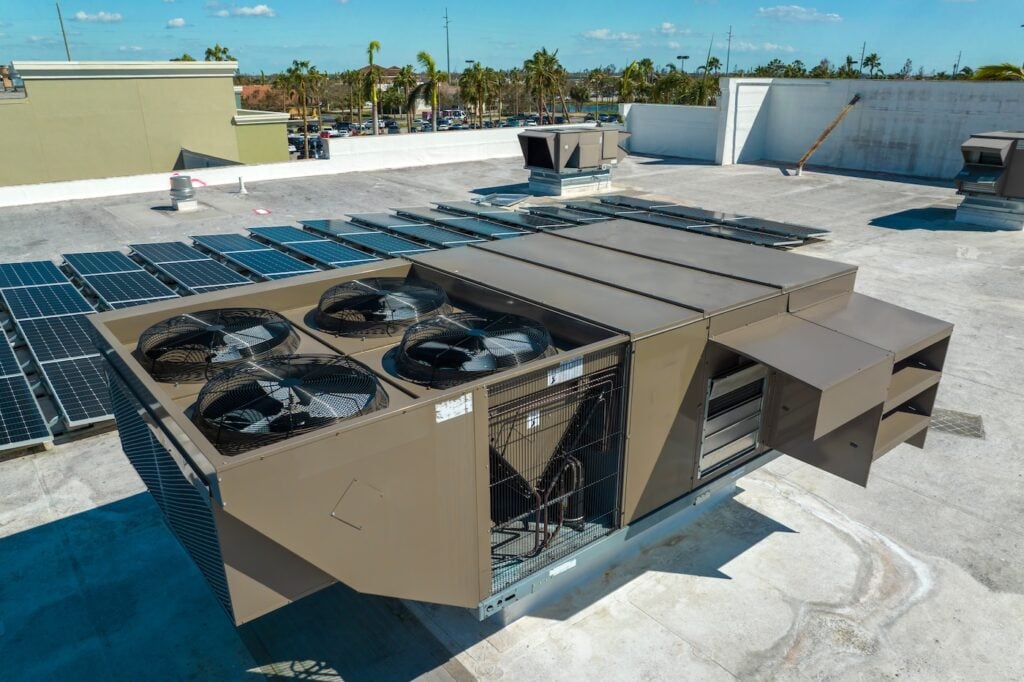 External unit of commercial air conditioning and ventilation system installed on industrial building roof. Exhaust vent on flat factory rooftop.