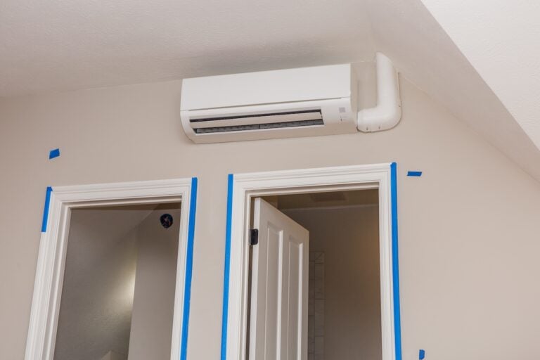 Room with painter's tape around doors and mini-split air conditioning unit installed above doors