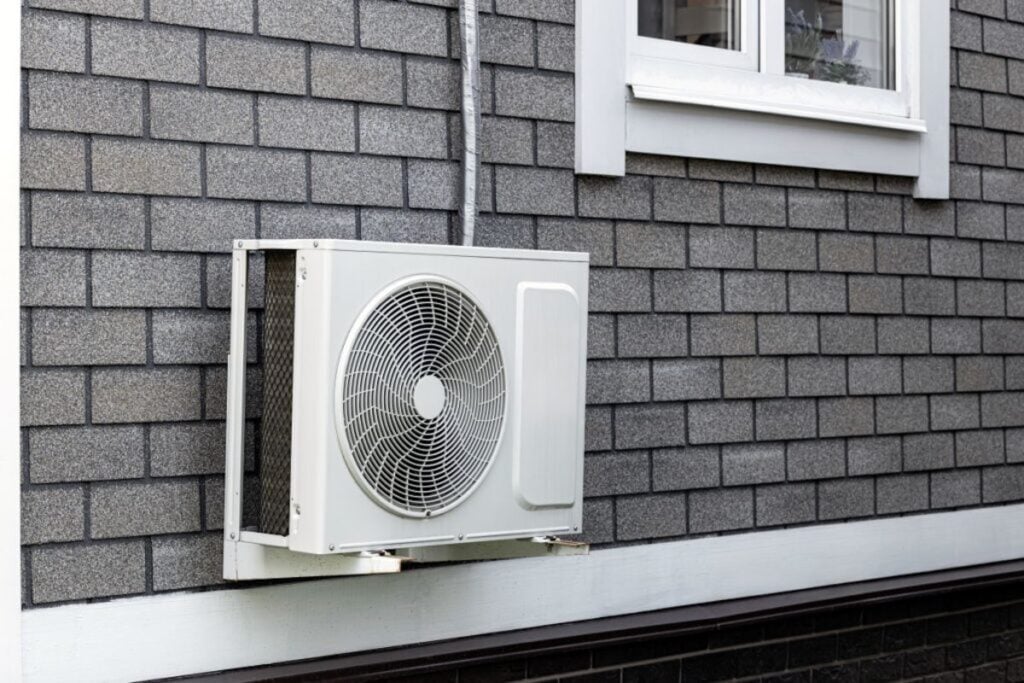the-external-unit-of-the-air-conditioner-is-attached-to-the-wall-of-the-house
