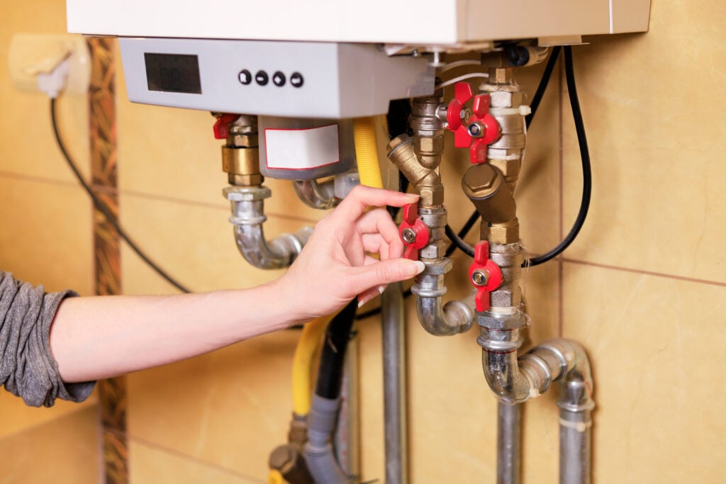 A woman checks if everything is OK with the gas furnace heating water in the house.