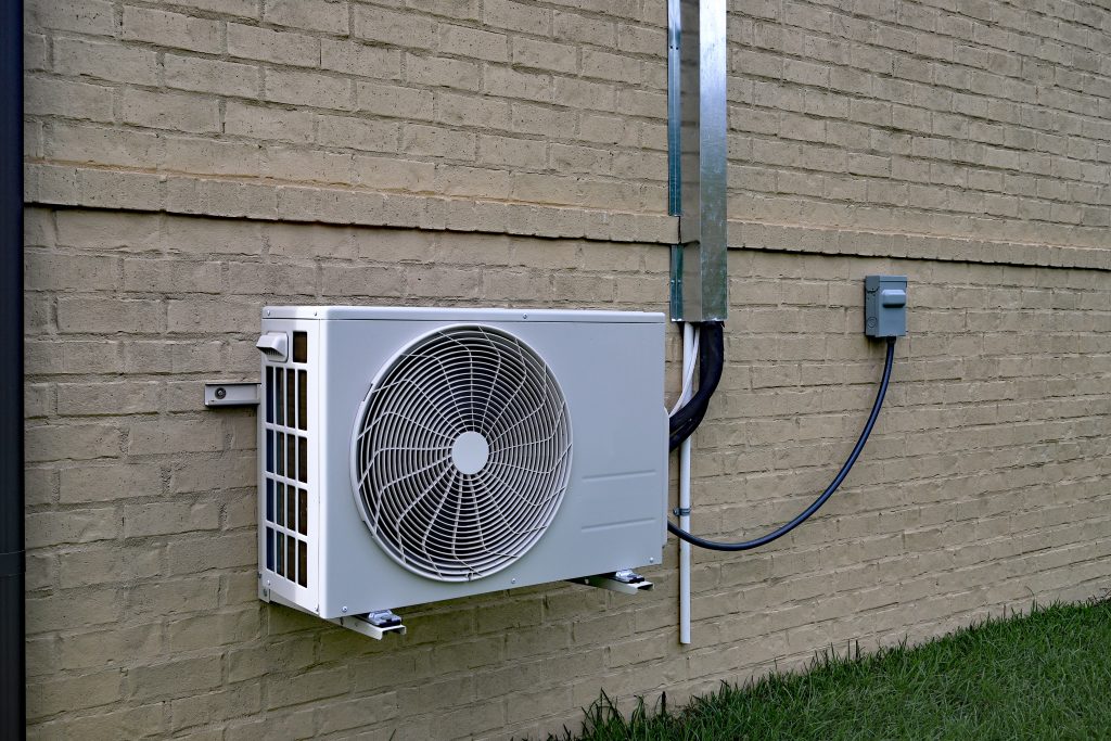 ductless heat pump installation Air Conditioner mini split system next to home with painted brick wall and space for text copy