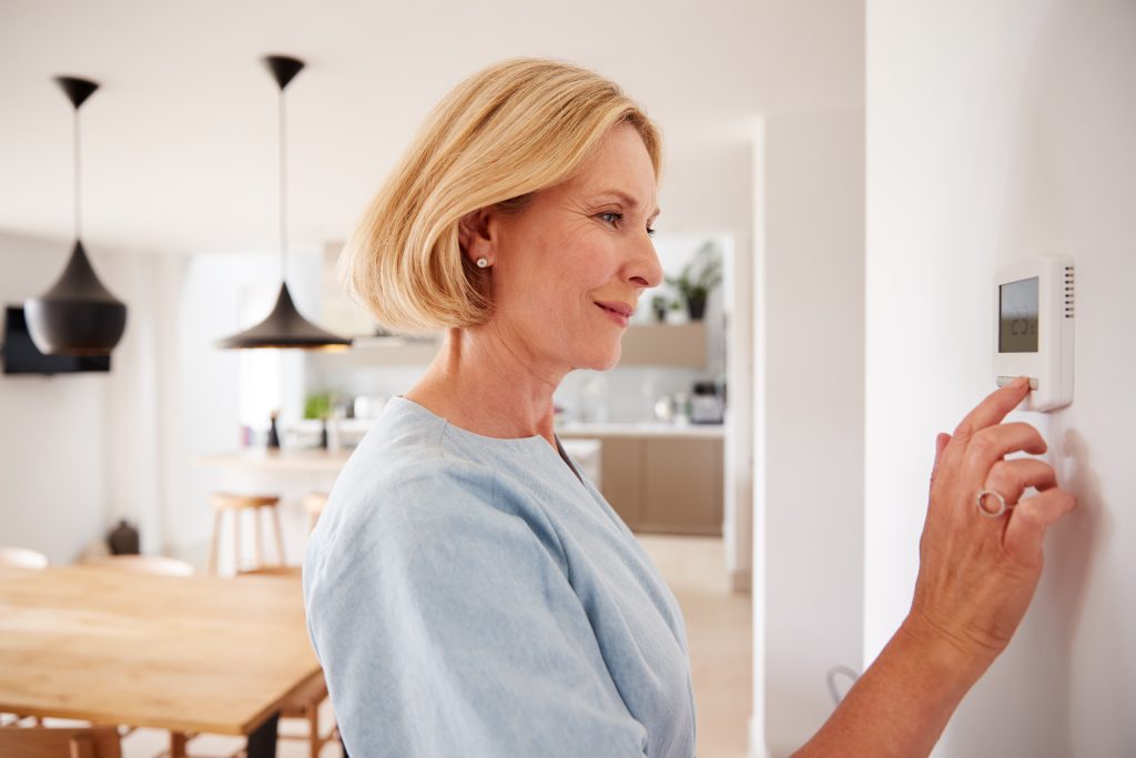 ac not cooling Close Up Of Mature Woman Adjusting Central Heating Temperature At Home On Thermostat